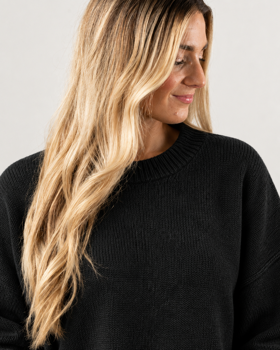 Model wearing black oversized knit pullover sweater, close-up neckline detail